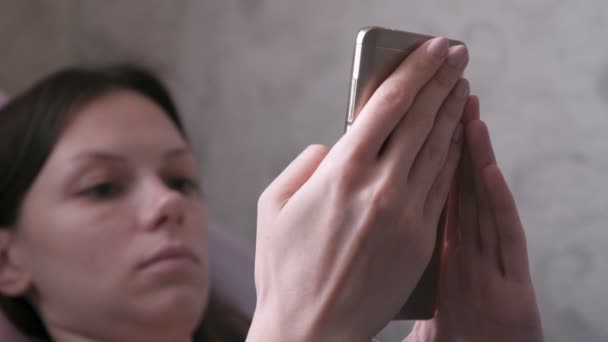 Relajante mujer acostada en el sofá y leyendo algo en el teléfono móvil. Cara de primer plano . — Vídeo de stock