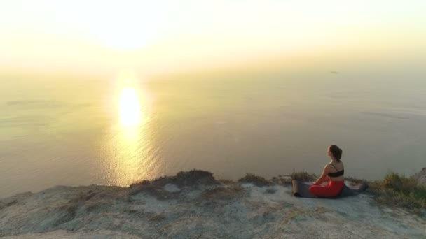 Bela vista da mulher fazendo ioga Baddha Konasana, Ângulo Ligado Pose na montanha com vista para o mar ao pôr do sol . — Vídeo de Stock