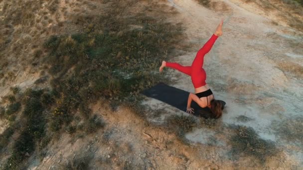 Žena dělá jógu poslušně na vrcholu hory při západu slunce. Letecké záběry krásné. — Stock video
