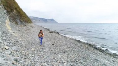 Kız bodyflex sırasında nefes egzersizleri rock ve deniz arka plan üzerinde bodur hamle yapıyor.