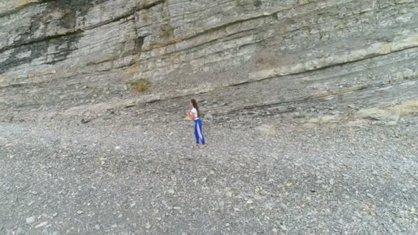 Vrouw doet yoga en fysieke oefeningen voor de benen op rock achtergrond. Luchtfoto mooi beeldmateriaal bekijken. — Stockvideo