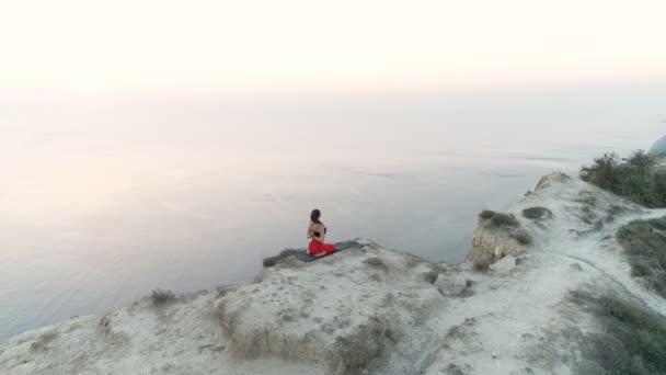Krásný výhled na žena dělá jógu nantasana, sklopná boční nohu zvedněte na hoře s výhledem na moře při západu slunce letecké záběry. — Stock video