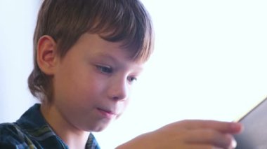 Mutlu çocuk tablet, yüz yakın çekim oyun oynuyor.