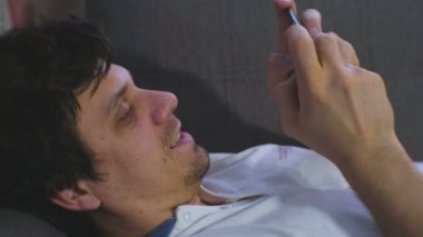 Adam cep telefonu evde kanepede döşeme üzerinde oyun çalış.