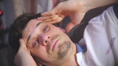 Genç adam kanepede yatan bir baş ağrısı ile.