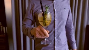 Barmen bir alkol kokteyl ile köpüklü şarap, buz ve içki bardağı içinde hizmet vermektedir, masanın üzerine koyar. Eller yakın çekim.