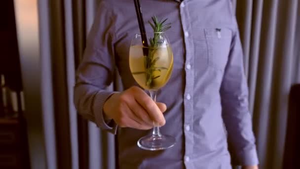 Barman serves a alcohol cocktail with sparkling wine, ice and liquor in wineglass, puts it on the table. Hands close-up. — Stock Video