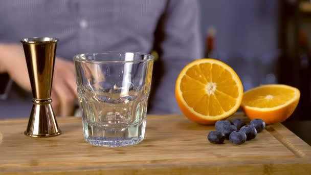 Bartendern häller tequila från jigger till stenar glas förbereder alkohol cocktail. Händer närbild. — Stockvideo