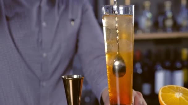 Barman mixen alcoholische cocktail op Champagne fluit met grote lepel en zet rietjes. Close-up van de handen. — Stockvideo