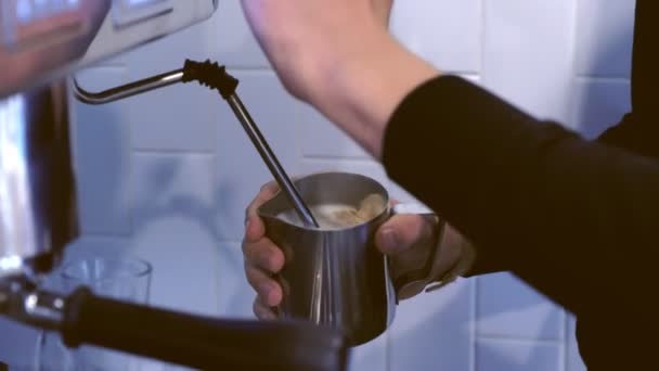 Professionale uomo barista preparare caffè fresco capuccino con generatore di vapore, tenendo brocca con latte fumante. Mani in primo piano . — Video Stock