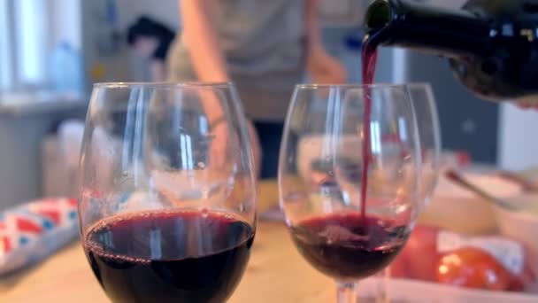 Rode wijn wordt gegoten in de wijnglazen in de keuken thuis. — Stockvideo