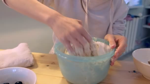 Woman kneads pizza dough by hands in bowl at home. Hands close-up. — Stock Video