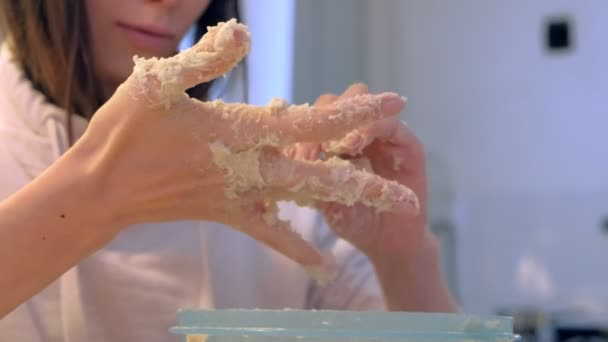 Женщина кларнирует руки от теста, готовит тесто для пиццы в миске на домашней кухне . — стоковое видео