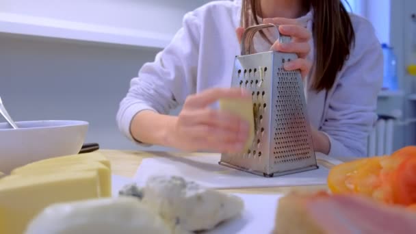 La donna strofina il formaggio sulla grattugia a casa in cucina. Mani in primo piano . — Video Stock