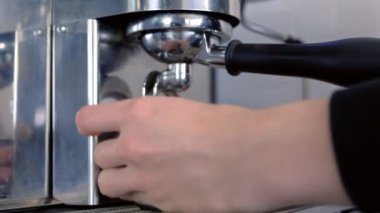 Barista sürahi ve bardak taze espresso kahve makinesi üzerinden dökülen. Eller yakın çekim.