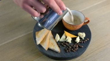 Barista sürahi taze peynir kahve Kupası eritilmiş peynir ve ekmek üzerine dökülen. Eller yakın çekim.