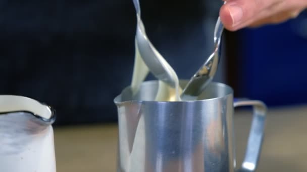 Barista puts melted cheese to coffee in pitcher and mix it. Makes cheese coffee. Hands close-up. — Stock Video