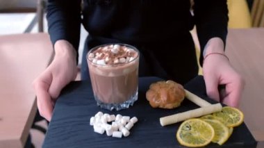 Garson kaya cam ahşap siyah tepside kek ve limon ile servis müşteri kakao hatmi ile siparişe taşır. Eller yakın çekim