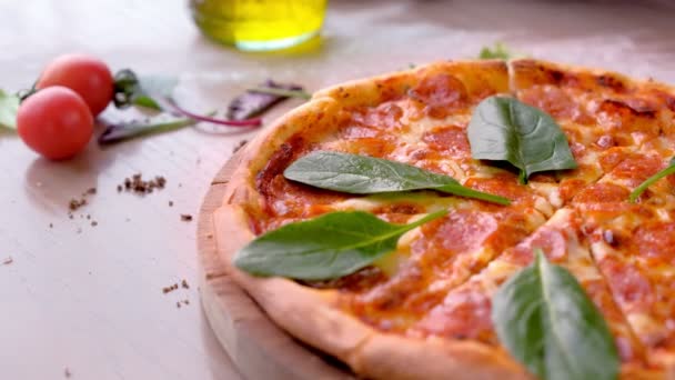 Cook takes a slice of salami pizza with spinach leaves, hands in rubber gloves close-up side view. — Stock Video
