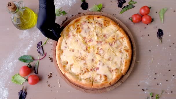 Cook neemt een plak van pizza met een gehandschoende hand. Close-up van de hand. — Stockvideo