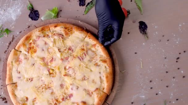 Cook takes a slice of cheese and bacon pizza with a gloved hand. Hand close-up. — Stock Video