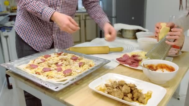 Молода сім'я готує салямі піцу разом на кухні. руки крупним планом . — стокове відео