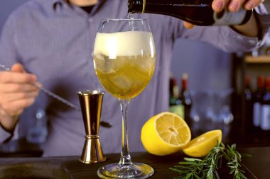 Barmen bir bardağı buz ve içki alkol kokteyl yemek için bir şişe köpüklü şarap dökülen. Eller yakın çekim.