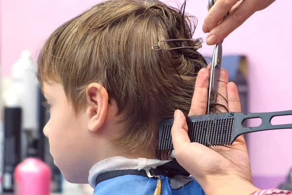Kadeřník řezání vlasy s nůžkami na chlapci hlavu. Pohled, stylisté ruce detail zezadu. — Stock fotografie