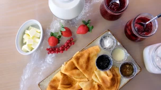 Hagyományos orosz palacsinta, a blini. Lekvárok, tejföl, tej és eper tányérra tálalva. — Stock videók