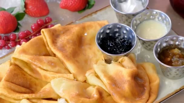 传统的俄罗斯煎饼, blini 配果酱, 酸奶油, 和草莓在盘子里。特写视图. — 图库视频影像