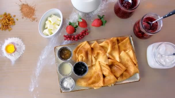 俄罗斯传统的煎饼, 在盘子里放了果酱、酸奶油和草莓。特写镜头顶部视图. — 图库视频影像