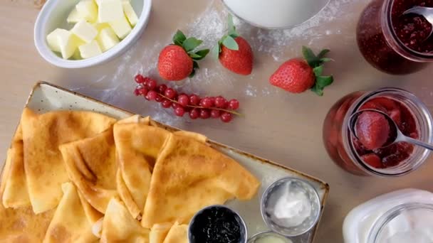 Crêpes russes traditionnelles, blinis servis avec confitures, crème sure et fraise dans l'assiette. Gros plan vue du dessus . — Video