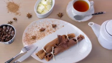 Çikolata Rusça krep blini plaka üzerinde doldurma lor ile. Bir fincan çay ve tereyağı ile hizmet.