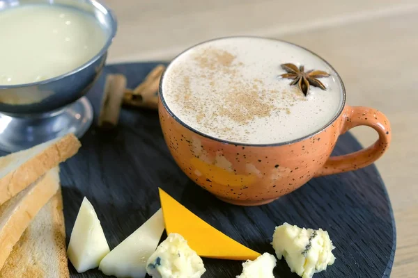 Cheese coffee with melted cheese, pieces of cheese and bread toasts on a tray.