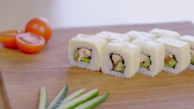 Tavuk, salatalık, yeşil ve krem chesse rulo üstte ahşap tahta sebze ile servis.