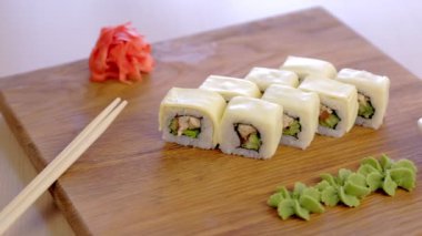 Wasabi, Marine, kırmızı zencefil, soya sosu ve sebze ile ahşap tahta üzerine tavuk, salatalık, yeşil ve krem chesse ile rulo.