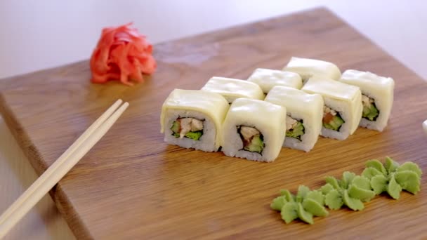 Rullar med kyckling, gurka, gröna och cream chesse på toppen på träskiva med wasabi, marinerad, röd ingefära, soja sås och grönsaker. — Stockvideo