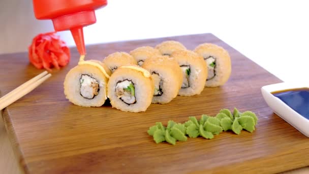 Verter rollos con salsa servida sobre tabla de madera con wasabi, jengibre rojo y salsa de soja . — Vídeos de Stock
