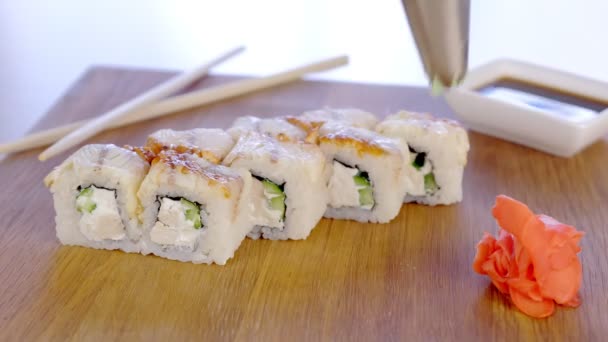 Šéfkuchař nabízí rohlíky s rybami na vrcholu v Dřevěná deska s wasabi, zázvorem a sojovou omáčkou. Rukou detail. — Stock video