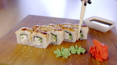 Kadın üstte ahşap tahta wasabi, zencefil ve soya sause ile servis balık ve susam tohumu ile rulo yiyor. Eller yakın çekim.