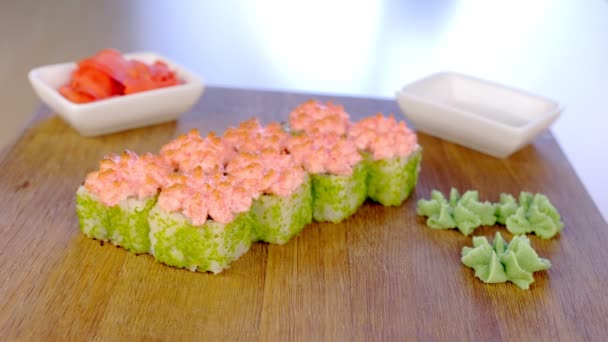 Kocken serverar rullar på träskiva med med wasabi, ingefära och soja sås. Hand närbild. — Stockvideo
