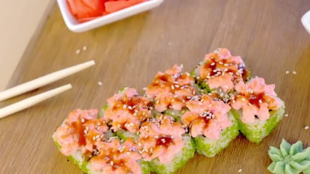 Rolls with green caviar and sauce on top on wooden board with with wasabi, ginger and soy sause, top view. — Stock Video