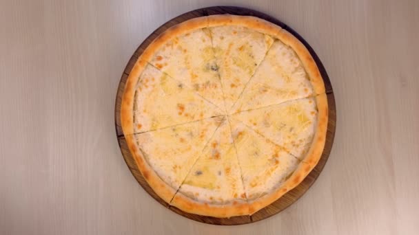 Pizza med olika sorters ost, skivning pizza på träskiva, närbild ovanifrån. — Stockvideo