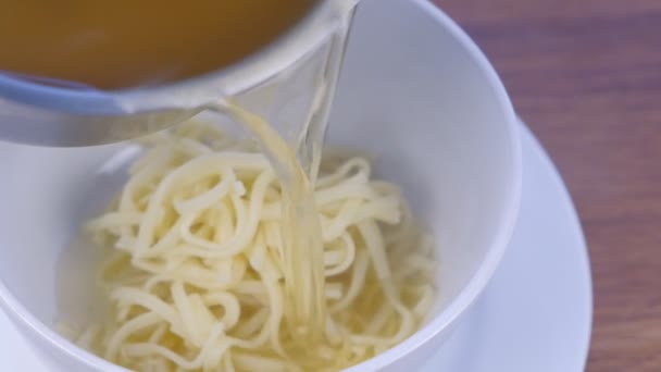Cook σερβίρει κοτόπουλο σούπα με ζυμαρικά σε λευκές μπολ. Χύνει ζωμός. — Αρχείο Βίντεο