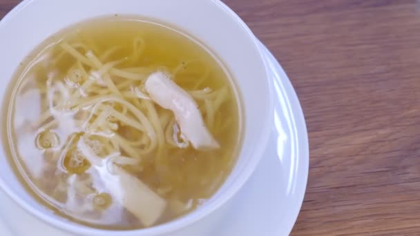 Куриный суп с лапшой в белой миске. Кусочки курицы, руки крупным планом. . — стоковое видео