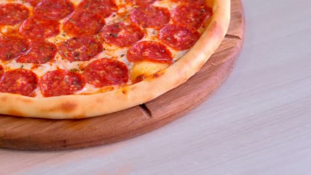 Helft van salami pizza op een houten bord op de tafel. Close-up weergave. — Stockvideo