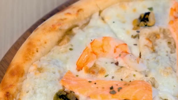 Cuarto de rebanada de pizza con mariscos y queso sobre tabla de madera, vista de cerca . — Vídeos de Stock