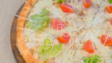 Tavuk ve peynir, domates ve marul üzerine ahşap tahta üzerinde pizza.