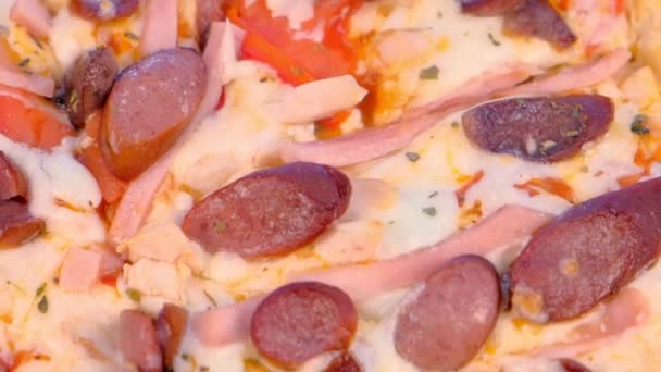 Πίτσα με καπνιστό λουκάνικο, ζαμπόν και τυρί. Το top view γκρο πλαν. — Αρχείο Βίντεο