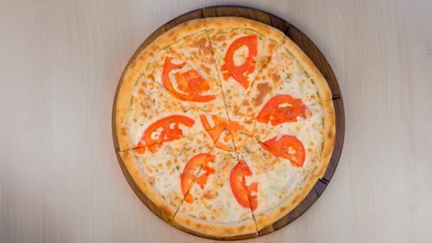 Rebanando pizza con tomates y queso sobre tabla de madera. Vista superior . — Vídeo de stock